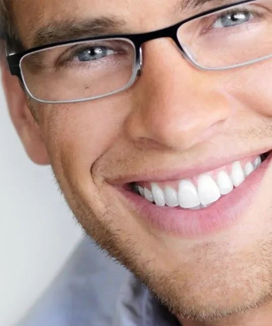 Close-up of a smiling man in glasses with bright, even teeth